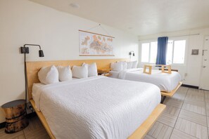 A hotel room with two beds, a map on the wall, and a window with curtains.