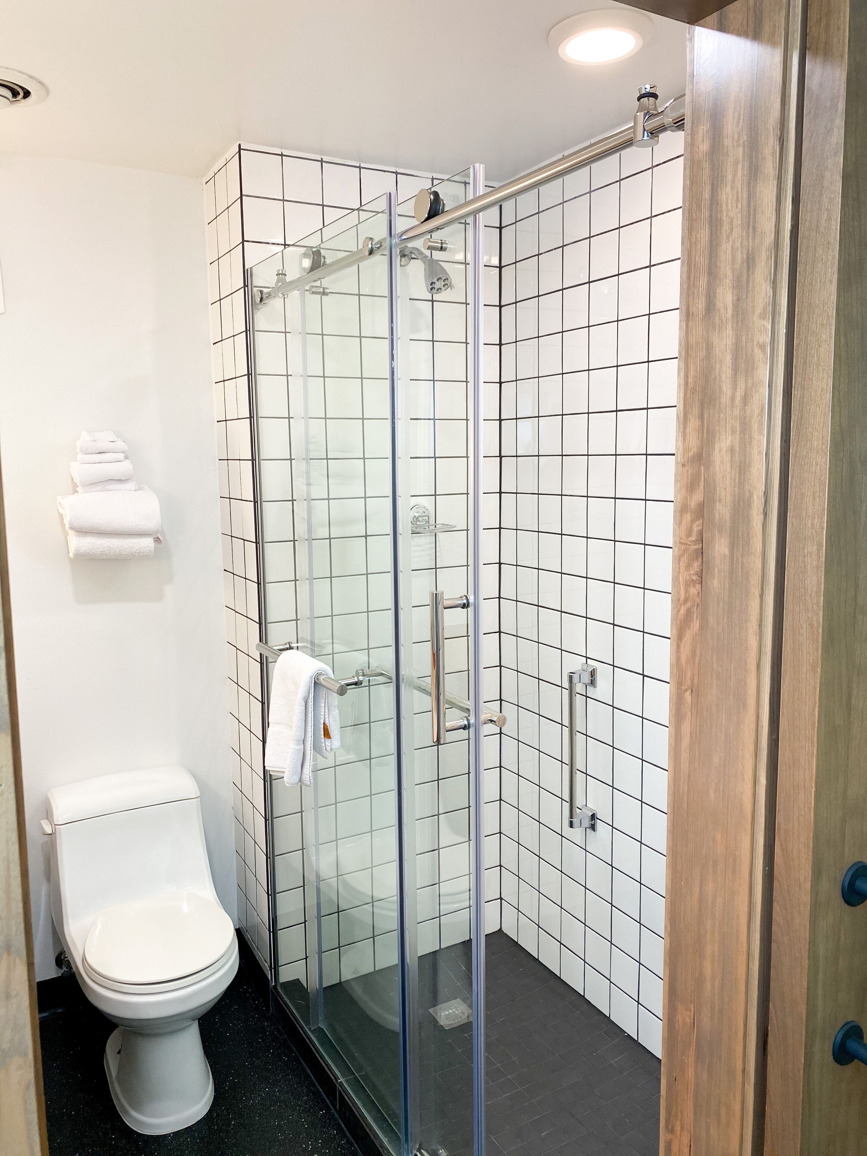 A modern bathroom with a glass-enclosed shower, a white toilet, and a tiled wall.