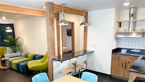 A modern kitchen with a wooden countertop, a dining table with chairs, and a kitchenette.