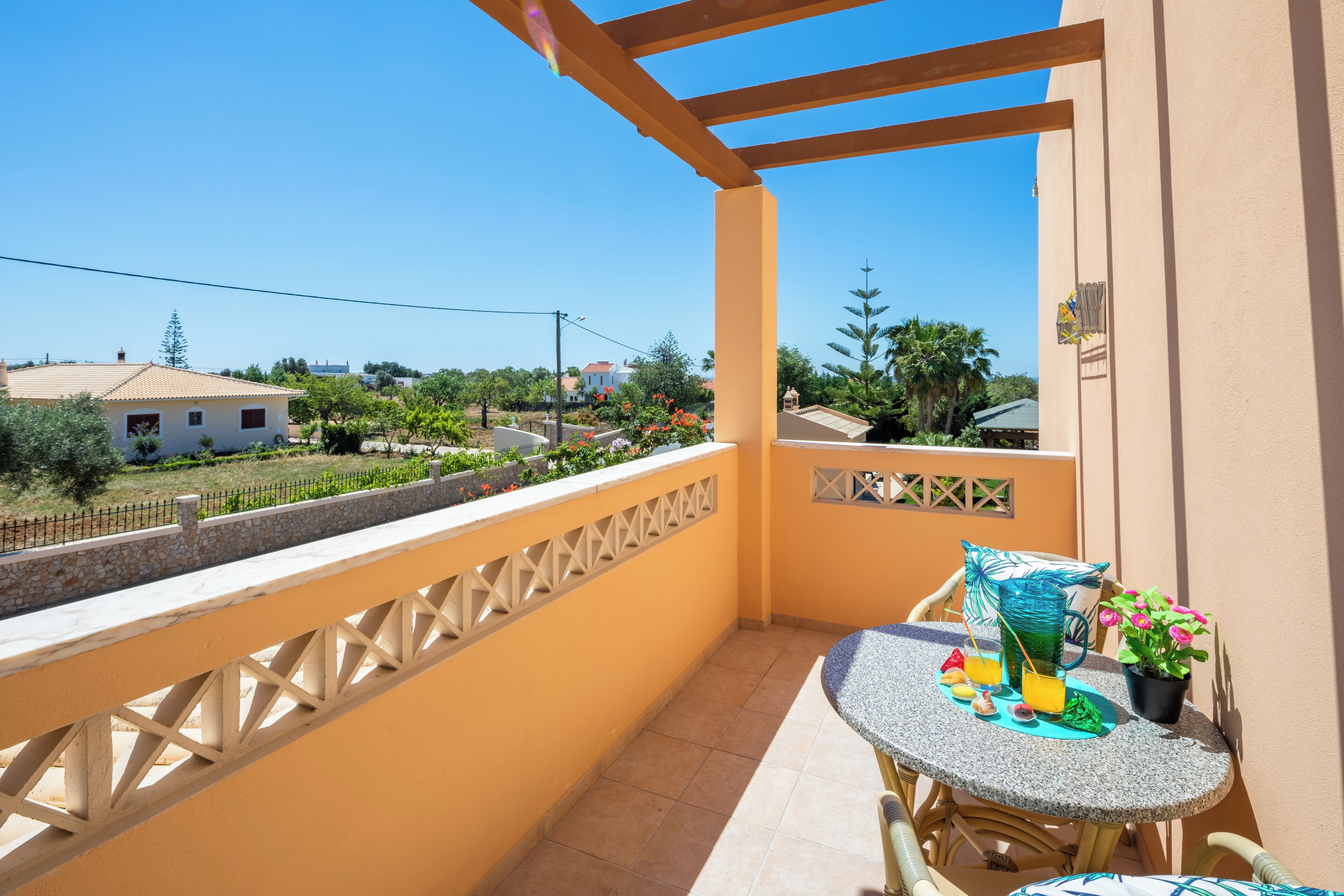 A balcony with a table, chairs, and a potted plant.