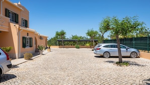 A paved driveway leading to a building with a car parked on the right.