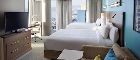 A hotel room with a large bed, a TV, a desk, and a view of the city.