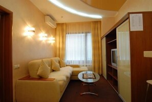 Relax in this cozy space with a comfortable sofa, coffee table, and TV on a stand.