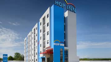 A modern hotel with a prominent "Hop Inn" sign, multiple floors, and a flat roof.