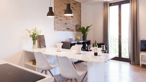 A modern kitchen with a white countertop, two pendant lights, and a brick accent wall. - Aspasios Charming Flats (Barcelona)