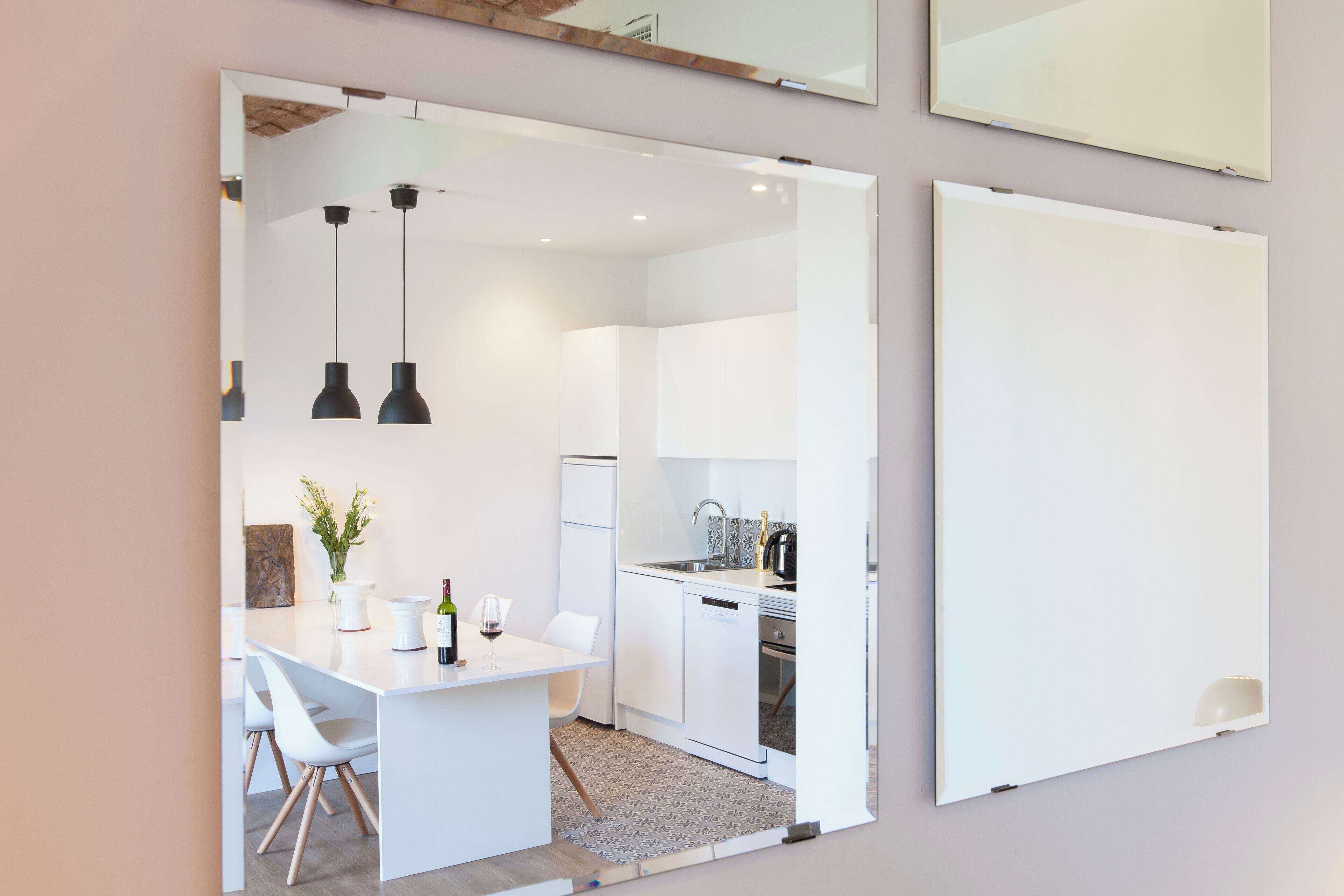 A modern kitchen with white cabinets, a dining area with a white table and chairs, and pendant lighting.