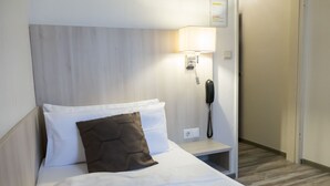 A hotel room with a bed, a nightstand, a lamp, and a phone. - Hotel Excelsior (Kassel)