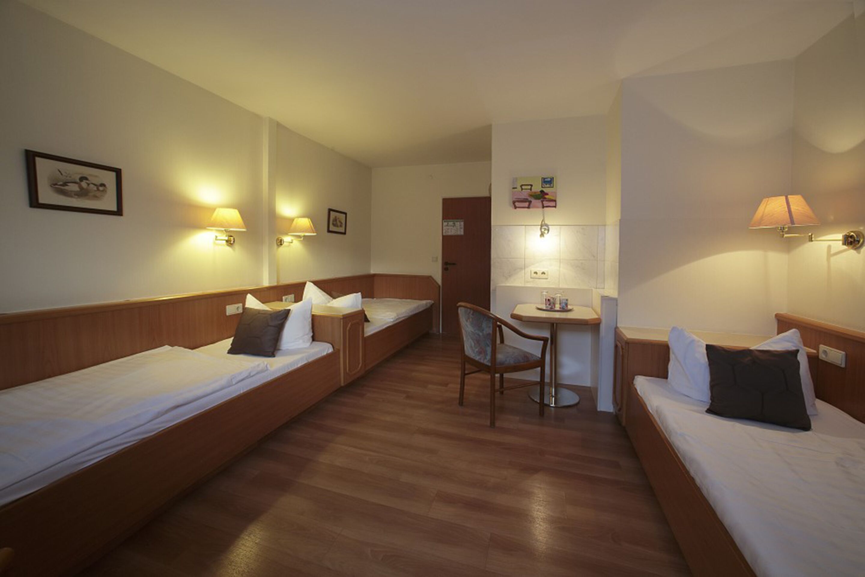 A hotel room with two single beds, a small table, and two chairs.
