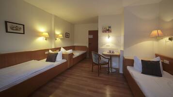 A hotel room with two single beds, a small table, and two chairs.