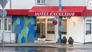 A hotel named HOTEL EXCELSIOR with a red awning, a colorful wall design, and a no parking sign. - Hotel Excelsior (Kassel)