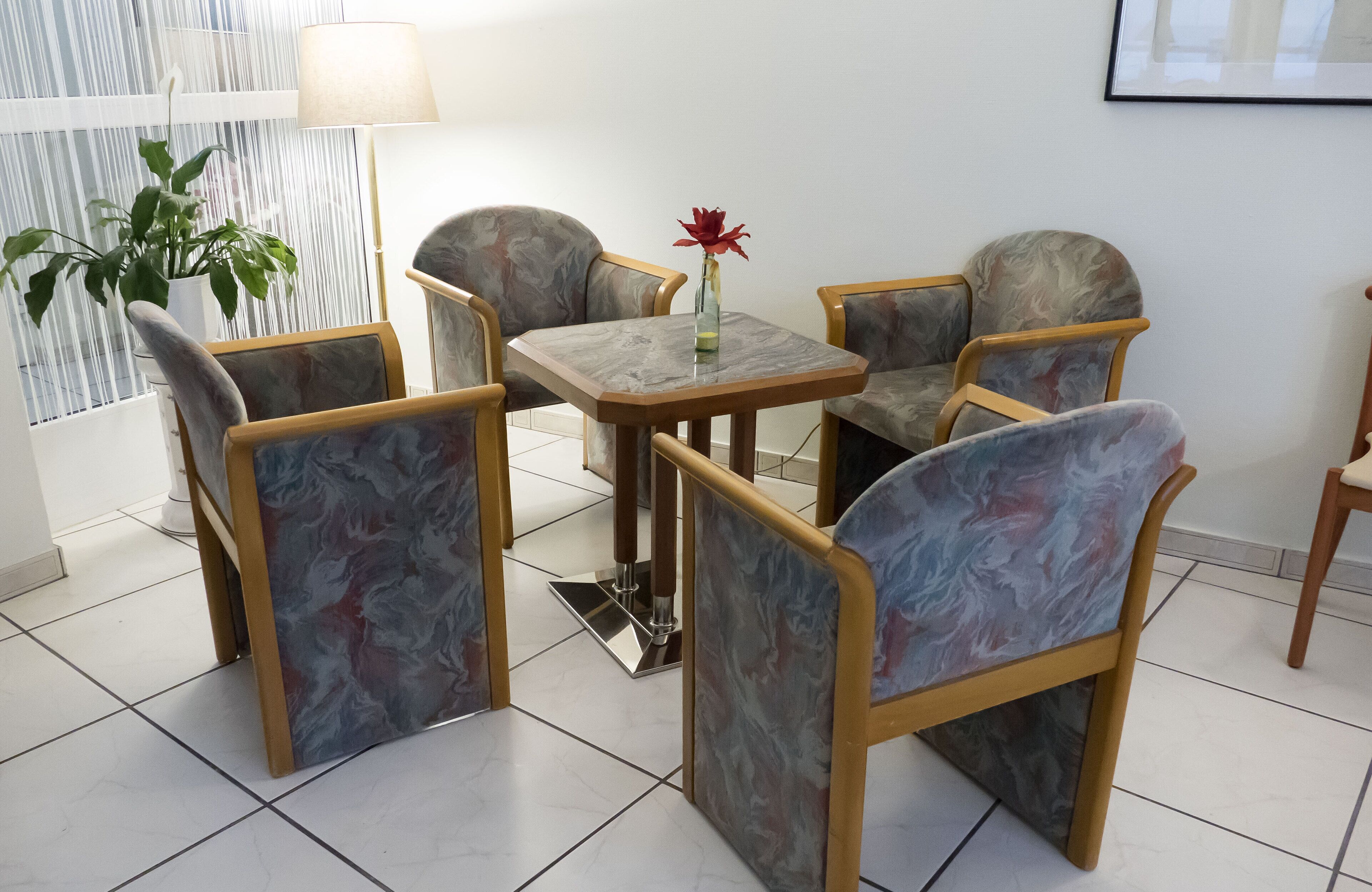 Una habitación con un sofá de estilo mármol, una mesita con un florero y una planta en maceta.