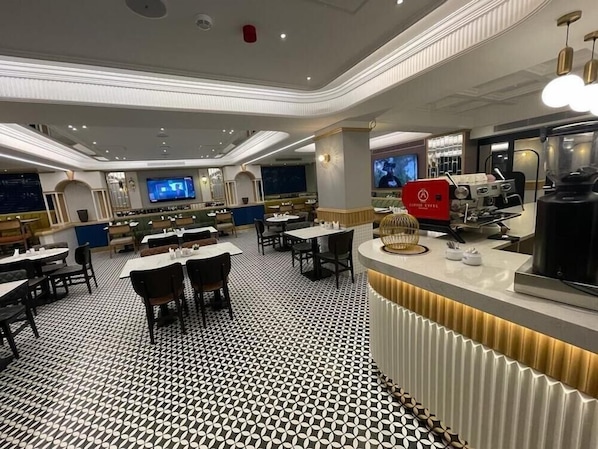 A modern restaurant with a patterned floor, multiple dining tables, and a central bar area with a coffee machine. - Eyfel (Istanbul)