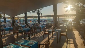 An outdoor dining area with tables and chairs, overlooking the sea. - Batihan Beach Resort & Spa Ultra All Inclusive (Kusadasi)