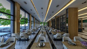 A modern restaurant with a long dining area, high ceilings, and large windows offering a view of the outdoors. - Batihan Beach Resort & Spa Ultra All Inclusive (Kusadasi)