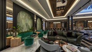 Ein moderner Lounge-Bereich mit grünen Sofas, einer Bar und einer großen Wanddekoration.