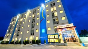 Ein mehrstöckiges Hotel mit einem gut sichtbaren 'Hop Inn' Schild, großen Fenstern und einem gut beleuchteten Eingang.