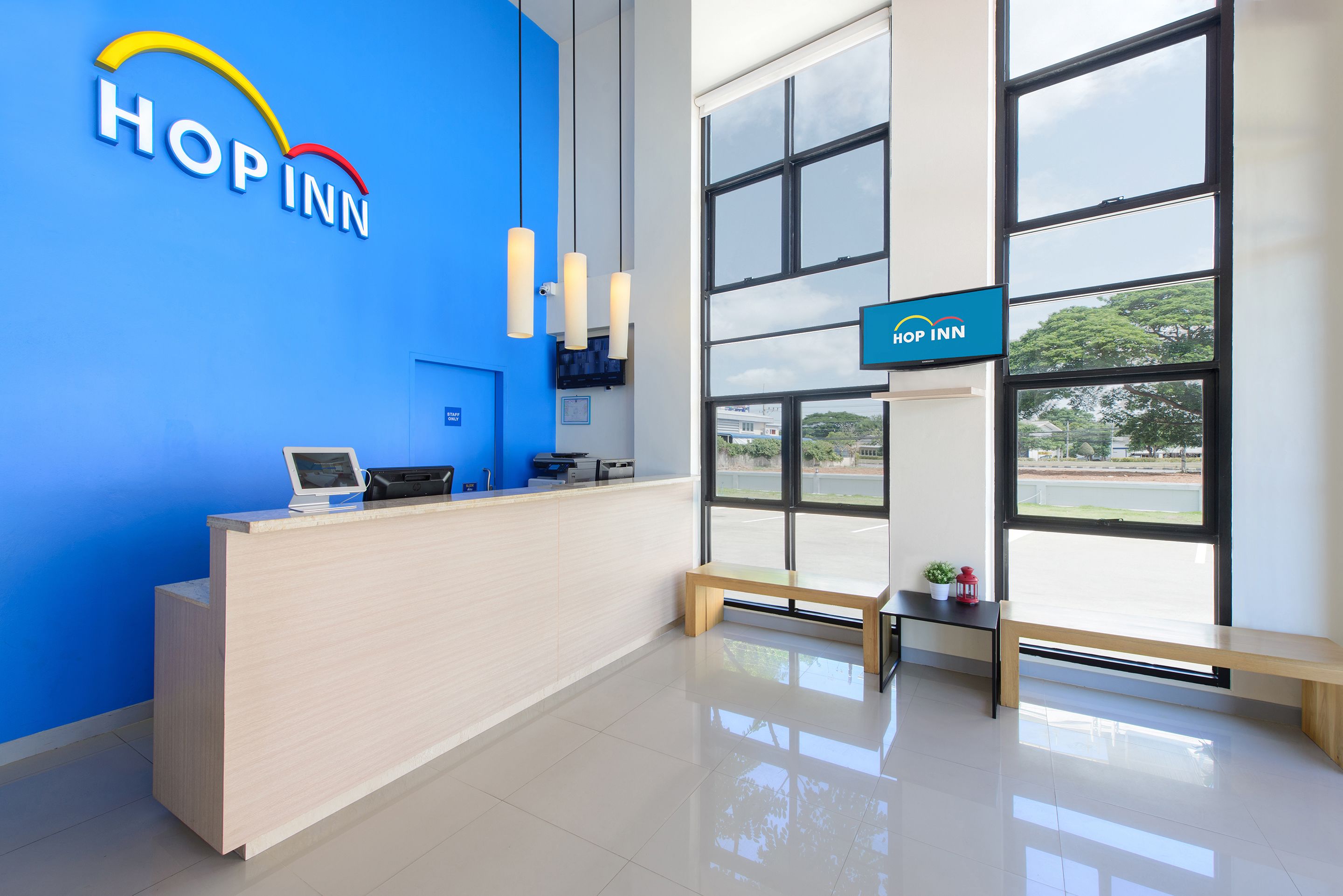 A reception area with a blue wall, a reception desk, a computer, and a bench.
