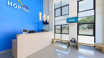 A reception area with a blue wall, a reception desk, a computer, and a bench.