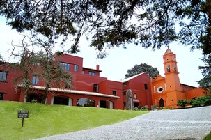 A red building with a bell tower and a sign reading "Misa Catolica".