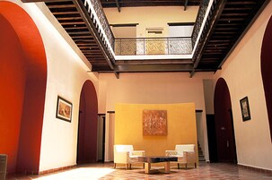A spacious lobby with a high ceiling, a central seating area, and a staircase leading to an upper level.