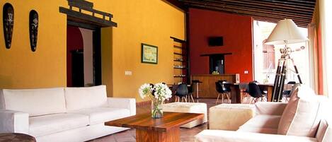 A living room with a white sofa, a wooden coffee table with a vase, and a red wall.