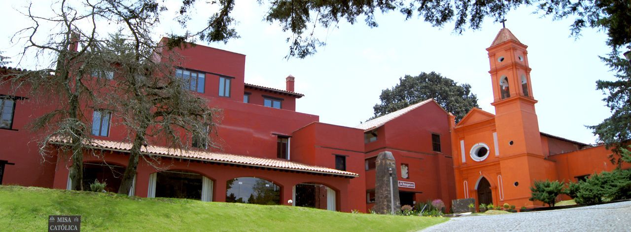 Un edificio rojo con una torre de campanas y un patio cubierto.