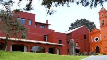 Un edificio rojo con una torre de campanas y un patio cubierto.