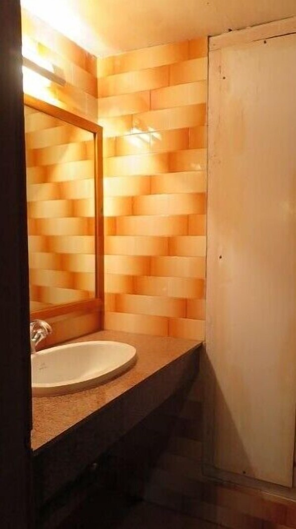 A bathroom with a wooden wall design, a sink, and a mirror. - Olathang Hotel (Paro)