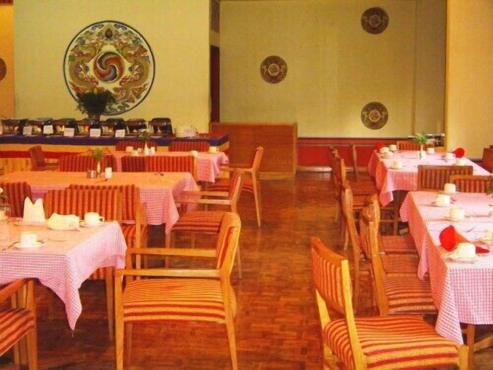 A dining area with multiple tables and chairs, each covered with a pink tablecloth.