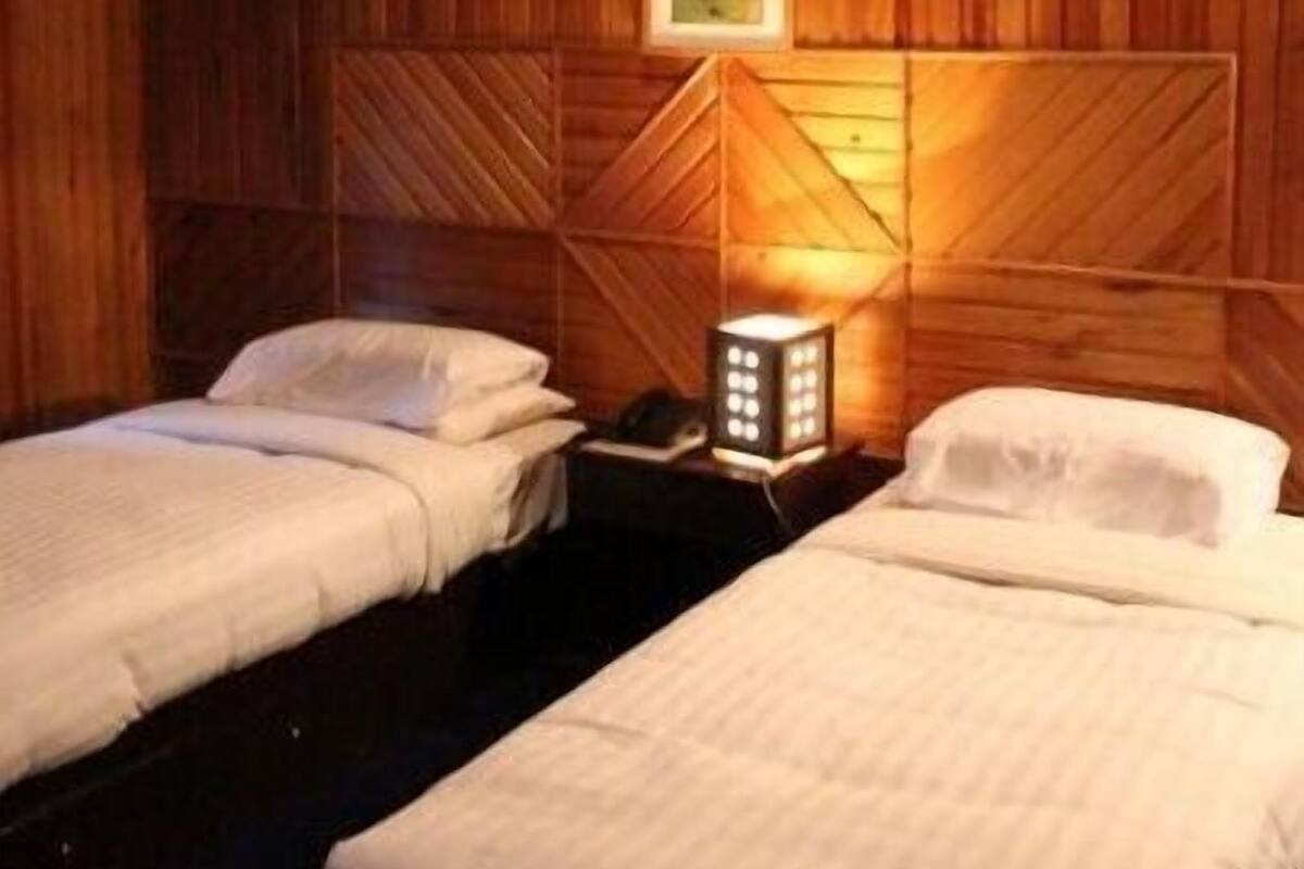 A room with two beds, wooden walls, and a framed picture on the wall.