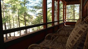 A room with wicker furniture and a view of a forest through large windows. - Olathang Hotel (Paro)
