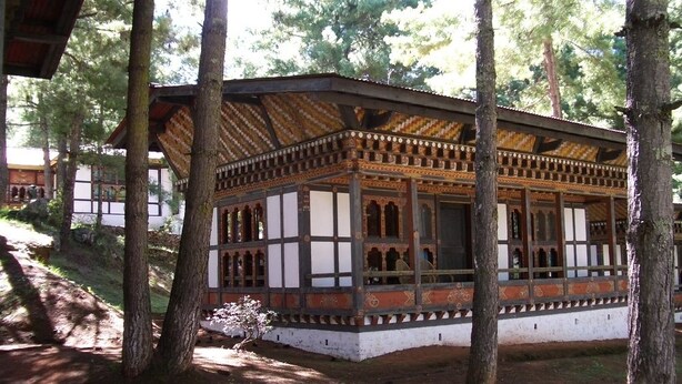 A traditional wooden structure with a balcony, surrounded by trees. - Olathang Hotel (Paro)