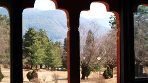 A window with a view of a forested landscape and mountains. - Olathang Hotel (Paro)