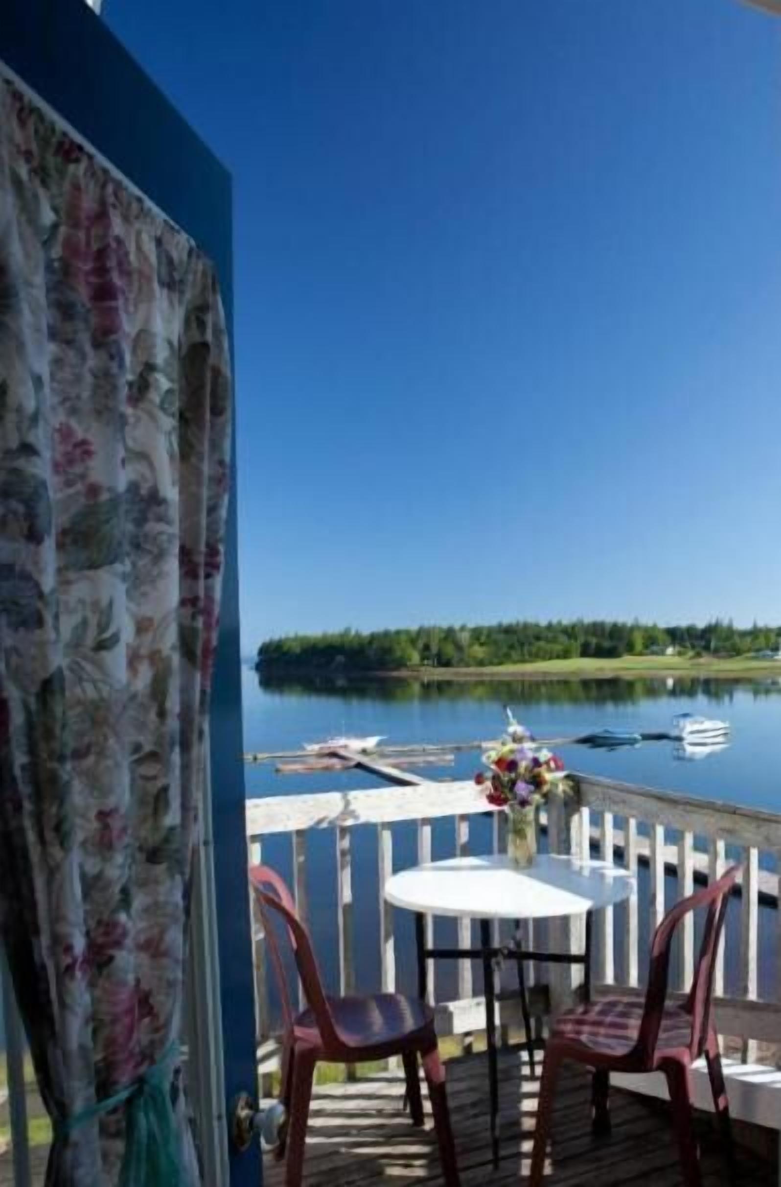 Una terraza con mesa y sillas que da a un lago tranquilo con barcos.