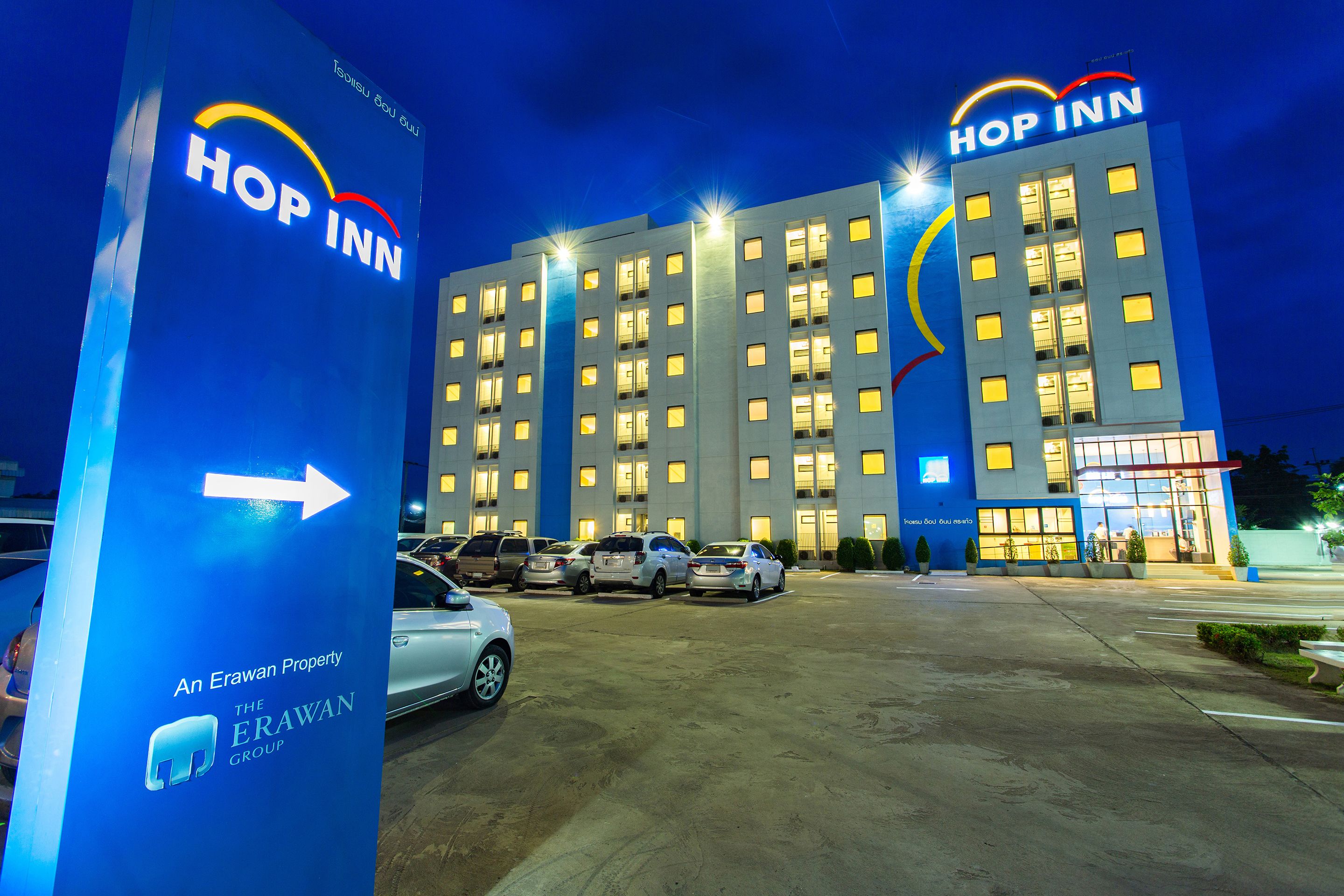 A hotel with multiple floors, a parking lot with several cars, and a prominent sign for the hotel.