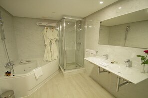 Une salle de bain moderne dotée d’une douche à parois de verre, d’une baignoire et d’un meuble-lavabo avec un miroir.