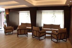 Un área de descanso moderna con sofás y sillones de cuero, ventanas amplias con vistas y suelo de madera.