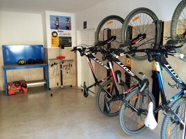 Una habitación con un banco azul, una bicicleta roja y negra, y otra bicicleta azul.