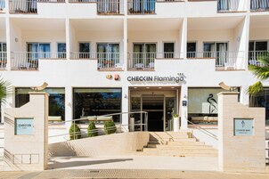 Entrada de un hotel con una escalera que lleva a la puerta, un cartel que indica Checkin Flamingo hotel y un letrero de bar lounge.