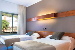 Habitación de hotel con dos camas, un ventanal con cortinas y una lámpara fijada a la pared.