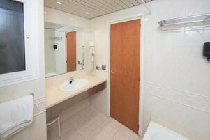 A bathroom with a sink, mirror, wooden door, and towel rack.
