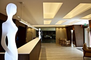 A modern hotel lobby with a reception desk, seating area, and a large illuminated sculpture. - Checkin Flamingo (Torroella de Montgrí)