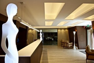 Un vestíbulo moderno de hotel con una recepción, zona de estar y una gran escultura iluminada.