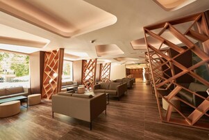 Un espacio lounge moderno con separadores de madera, asientos cómodos y vistas al exterior.