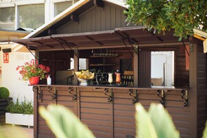 A wooden outdoor bar area with a counter, a bowl of fruit, and a pitcher.