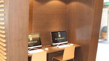 A wooden partition with two computer desks, each with a monitor displaying the Flamingo Hotel logo.