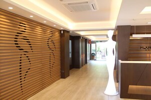 Un moderno hall de hotel con paneles de madera, un mostrador de recepción y un camino despejado hacia la salida.