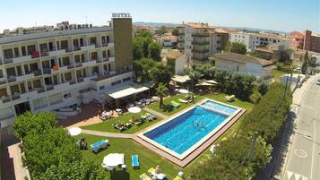 A hotel with a swimming pool, outdoor seating, and a view of the surrounding area.