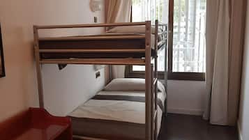 A bunk bed room with a window, a red chair, and a painting on the wall.