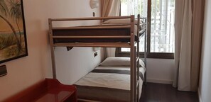 Habitación con literas, una ventana, una silla roja y un cuadro en la pared.